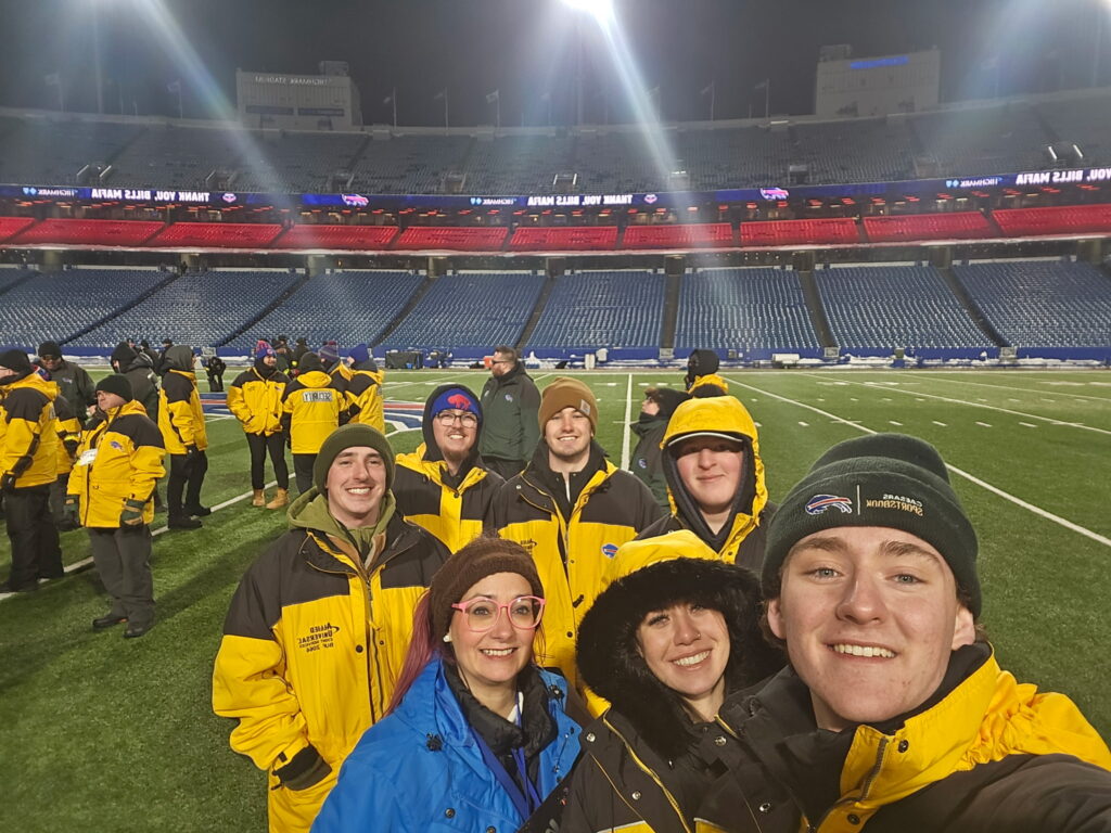 Tiffany Demiris, center left in a blue jacket, assistant professor of sports management at St. Bonaventure University, stands with students on the field at Highmark Stadium after a Buffalo Bills game where they worked to raise funds for campus organizations. (Photo courtesy of Hunter DiProsa)